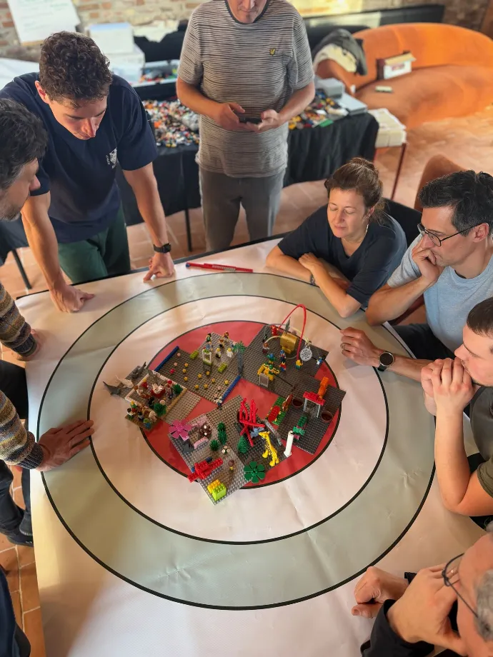 Deelnemers bespreken samen een gebouwd model aan tafel